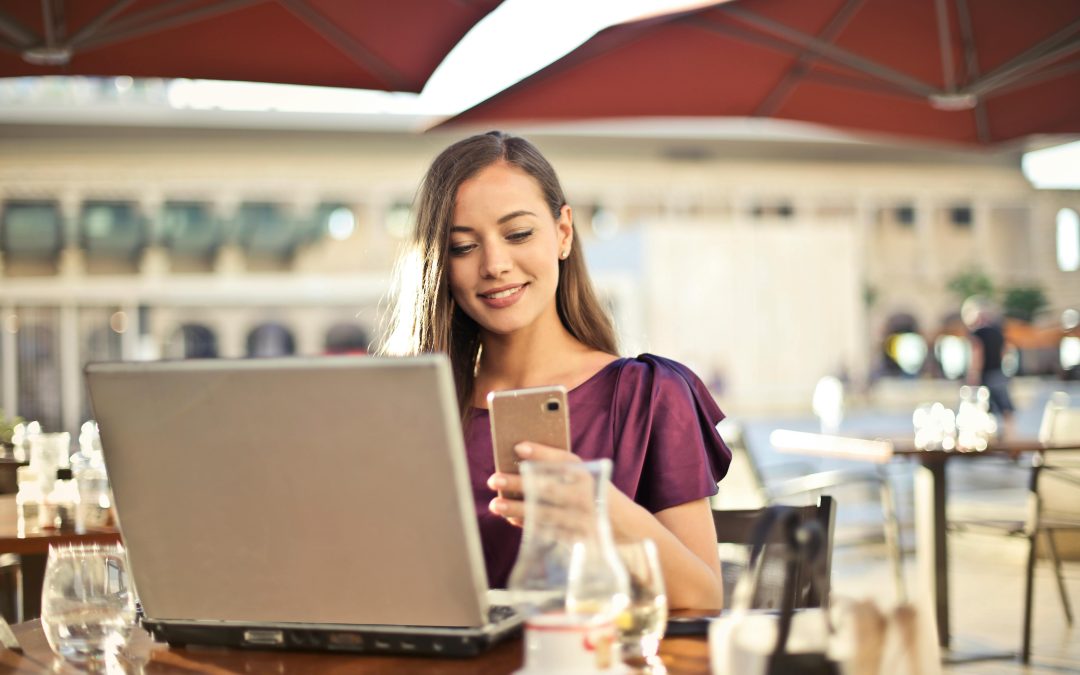 Woman calmly working on laptop and phone in café showing how to take action when overwhelmed